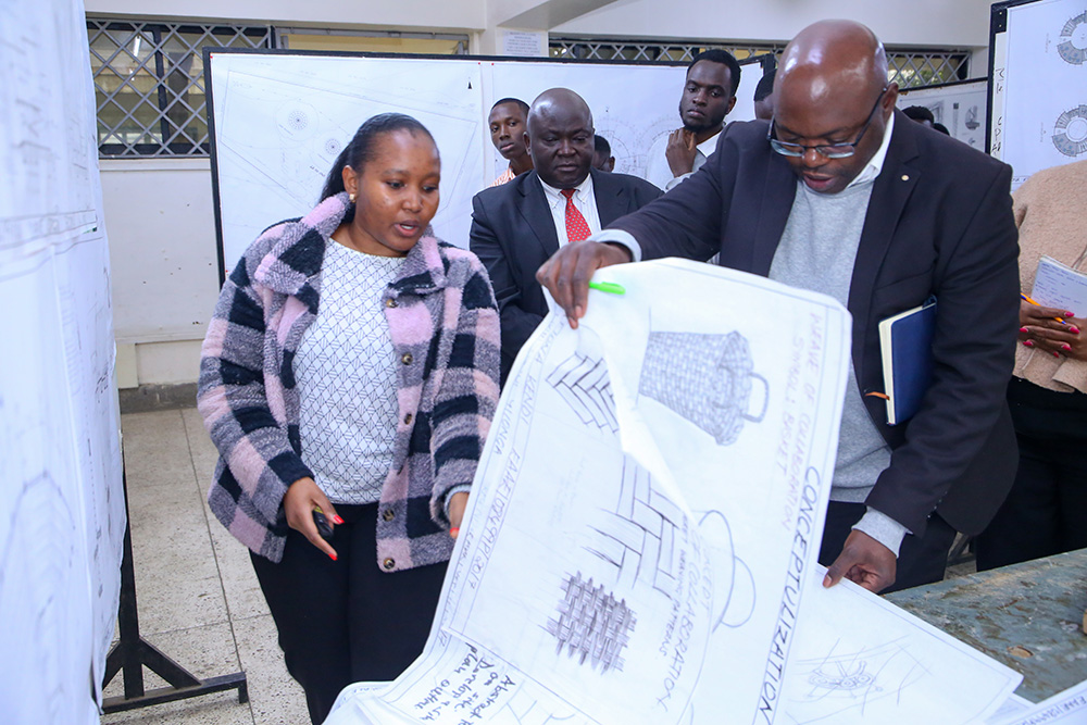 Fiona Kendi (Left) from the Department of Architecture, Design and Planning showcasing her project during students' exhibition. DVC, Academic and Student Affairs, Prof. Maurice Amutabi (Center) graced the occasion
